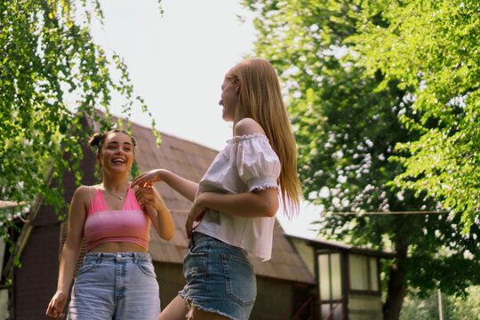 Yung female friends dancing in nature. With long hairs, buns and casual summer clothes. Enjoying the day together. 