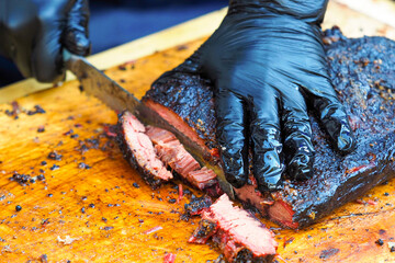 Brisket bbq smoked beef sincled in foil. Cutting the finished brisket with a knife