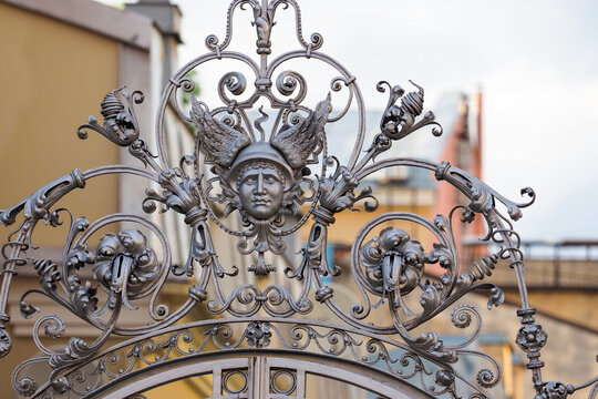 Decorative forged lattice with the image of the head of Mercury with wings and flowers. Furshtatskaya street, St. Petersburg, Russia