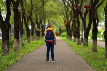 boy in a yellow sweatshirt with a backpack on his back going to school. back to school concept 