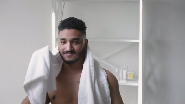 Morning hygiene. Bathroom routine. Spa freshness. Confident satisfied shirtless man drying wiping wet hair face with white towel after shower at light interior.