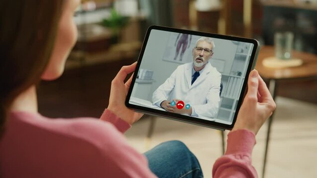 Young Girl Sick at Home Using Digital Tablet to Talk to a Doctor via Conference Video Call on Medical App. Beautiful Woman Checks Possible Symptoms with Professional Physician, Using Online Video Chat