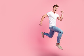 Fototapeta na wymiar Side view of brunette man running in air, hurrying for discounts empty copy space for advertising studio shot isolated pink background