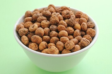 Chufa, tigernut, earth almond on ceramic bowl on green background with copy space for text. Healthy organic food concept. Tiger nut for flour, milk, traditional typical drink horchata Valencia Spain