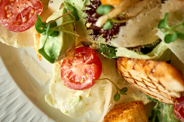 Caesar salad with grilled chicken in a plate. A selective trick. Close-up. Noise in post-production
