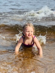 Fototapeta premium Little girl lying in sea in waves