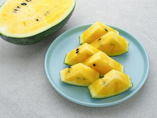 Slice yellow watermelon or semangka kuning in tosca plate on grey background. Selective focus.
