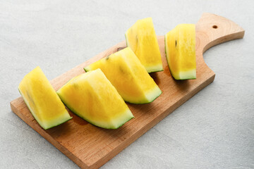 Slice yellow watermelon or semangka kuning in tosca plate on grey background. Selective focus.
