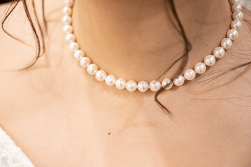 Take a close-up shot of the pearl necklace worn by the bride