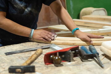 Hands of a female carpenter sanding wood