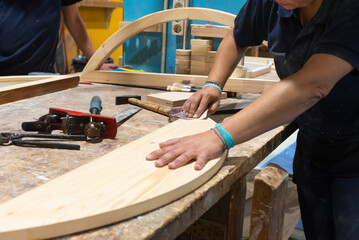 Hands of a female carpenter sanding wood