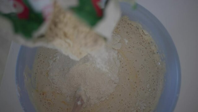 adding flour into the crapes batter and mixing with the wooden spoon 