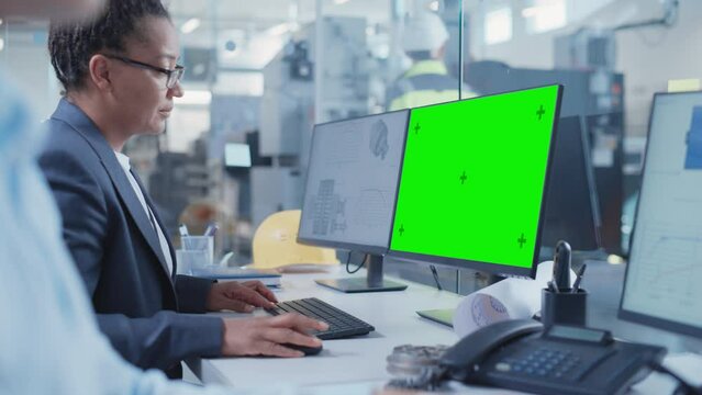 Factory Office Facility: Industrial Engineers Drafting Blueprints of a Heavy Industry Machine Parts on a Computer CAD Software. One Computer Monitor Display is a Green Screen Mock Up Template.