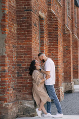 Obraz na płótnie Canvas Stylish beautiful fashionable couple in fashionable casual clothes poses together on the street near brick wall