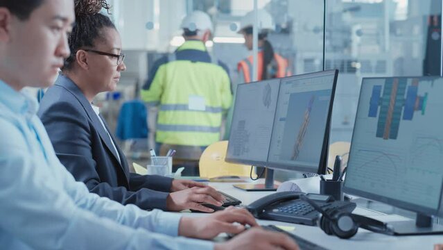 Factory Office Room: Industrial Engineers Developing Models of a Heavy Industry Machine Parts on a Computer 3D Software. Modern Technological Industry 4.0 Research and Development Center.