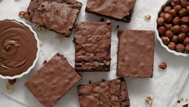 Fresh homemade chocolate brownie served with hazelnuts and melted cream