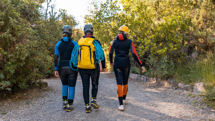 Tres mujeres irreconocibles, andando por la montaña, con el equipaje de barranquismo. Fotografía...