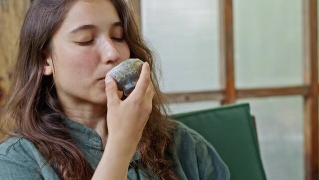 Young woman stares at small stone cup and drinks tea closeup. Young woman discovers small handmade Japanese stone cup and takes sip of tea. European lady wants to learn more about tea ceremony closeup