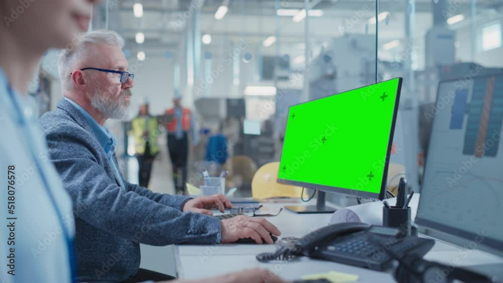 Poster Factory Office Facility: Industrial Engineer Drafting Blueprints of a Heavy Industry Machine Parts on a Computer CAD Software. One Computer Monitor Display is a Green Screen Mock Up Template.