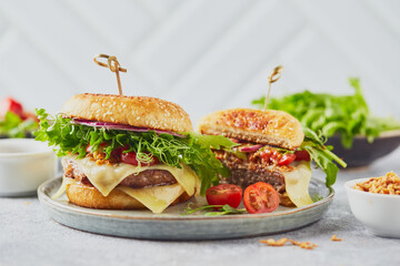 Two burgers with veal cutlet and herbs on wooden cutting board