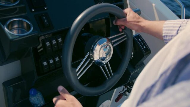 Male hand on rudder, steering wheel of motorboat floating down the river, close up shot.Luxury motorboat yacht in navigation.Slow Motion