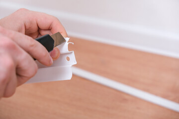 A man cuts the floor skirting boards to a suitable size for installation in a room. Home renovation.