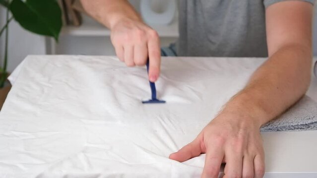 A man removes fabric pills using a disposable shaving machine. A razor for removing pellets.