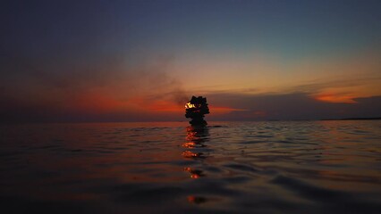 A fire burning in an artistic oven fireplace campfire chimney built in the Istria seaside water at a romantic sunset beach with small Mediterranean sea ocean waves in Croatia filmed in slow motion.