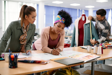 Young female designers working on new clothing line in fashion design studio.