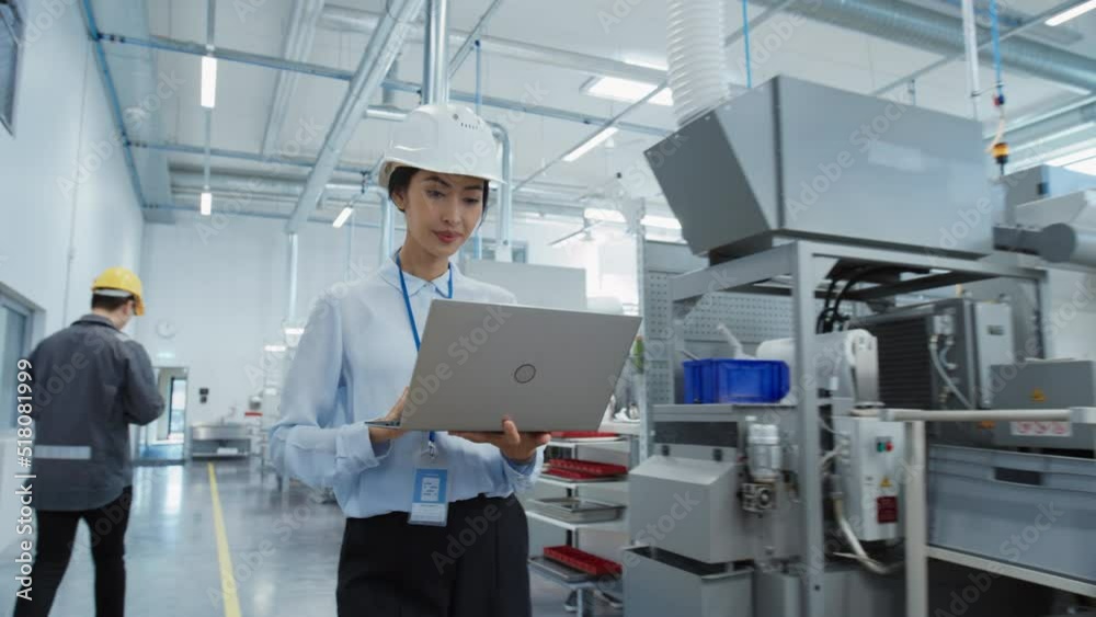 Leinwandbilder Portrait of an Asian Female Engineer in Hard Hat Walking and Using Laptop Computer at Electronic Manufacturing Factory. Technician Working on Daily Tasks and Research and Development Data.