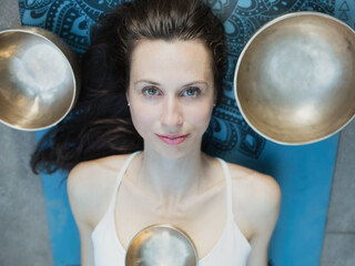 Yoga concept, meditation and sound therapy. Portrait of beautiful young caucasian woman surrounded...