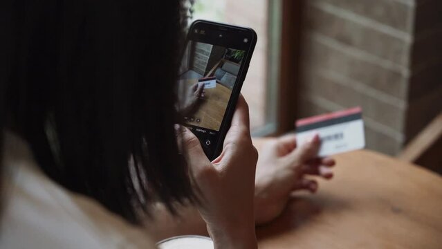 A young woman makes purchases through a smartphone with a bank credit card
