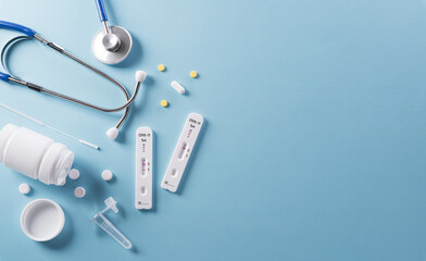 Covid-19 rapid antigen test, stethoscope and medicine on blue background. Worldwide coronavirus...