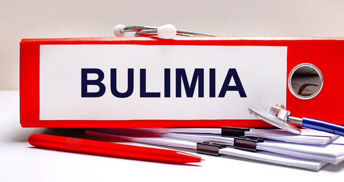 On the desktop is a stethoscope, documents, a pen, and a red file folder with the text BULIMIA. Medical concept