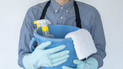 エプロンを着た男性と掃除道具