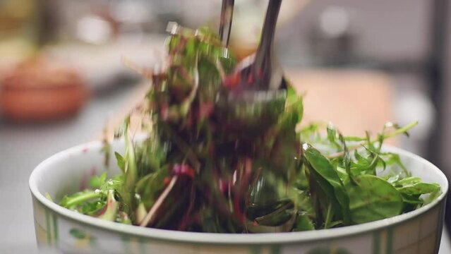 Stirring of fresh salad with dressing in a bowl, slow motion.