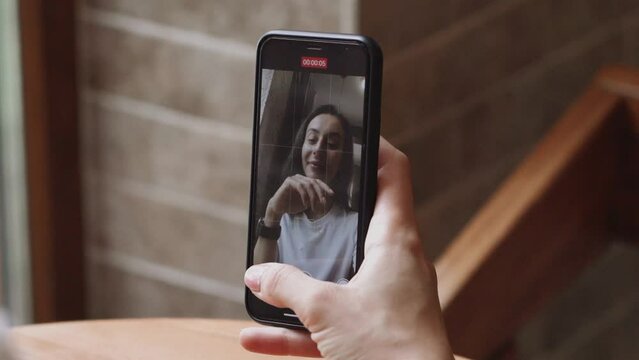 Beautiful  woman using a smartphone video calling, chatting online with her friend, family sitting in a cafe