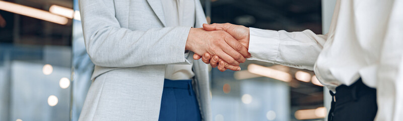 Close up of two confident businesswoman are handshaking before meeting in modern office.