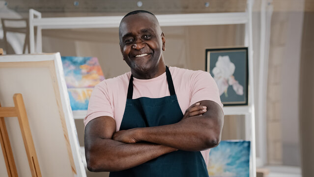 Portrait close up male happy old 50s painter art teacher African American happy elder senior middle-aged man artist talented designer creator posing crossing arms art studio finishing drawing pictures