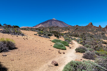Panoramic view on volcano Pico del Teide and Montana Blanca, Mount El Teide National Park, Tenerife, Canary Islands, Spain, Europe. Hiking trail to La Fortaleza from El Portillo. Barren desert terrain