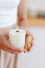 Candle in Hands of Light Background close-up. Place for Label. Minimalist Home Decor Style
