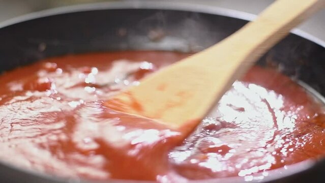Cooking and stirring delicious tomato sauce in the frying pan.