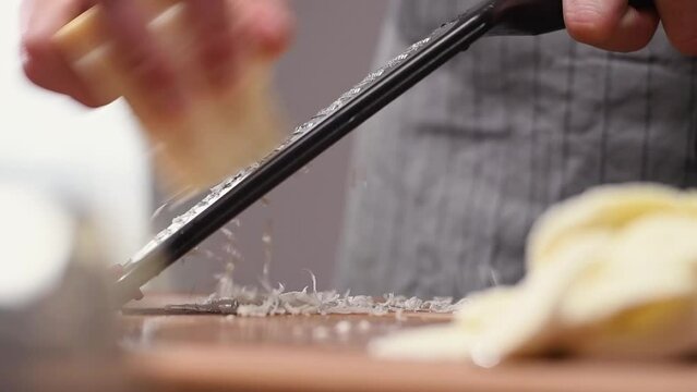 Grating parmesan cheese with a grater in the kitchen.