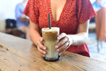 Fototapeta na wymiar Woman's hands holding a glass of ice coffee