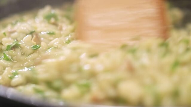 Cooking and stirring risotto with mushroom in the frying pan, slow motion.