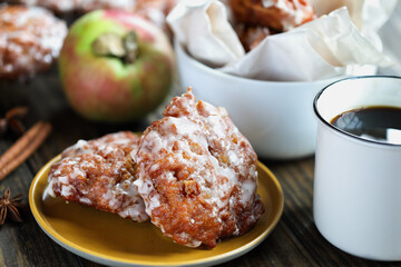 Glazed apple fritters and hot coffee with fresh apples, cinnamon bark and anise. Selective focus with blurred background and foreground. 