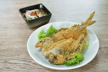 deep fried black-banded trevally fish with flake bread on plate dipping spicy and soy mango sauce 