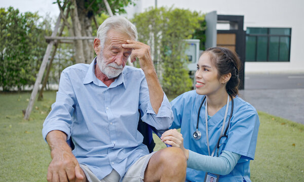 Depressed Male Patient Crying On Wheelchair. Young Nurse Caregiver Consoling Him. Unhappy Senior Man Having Geriatric Or Depression Disease. Therapist Taking Care, Giving Support And Empathy.