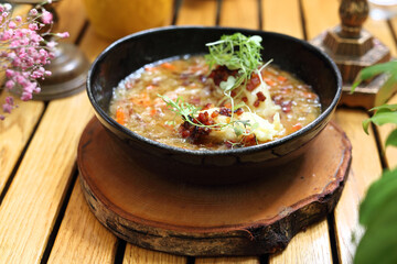 Dumplings in a sauerkraut soup, selective focus, close-up. Cabbage soup in a modern black bowl, on a wooden table.