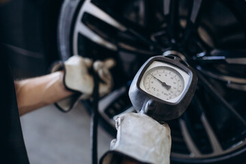 Repairman at car service checking wheel pressure